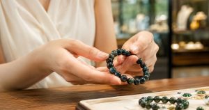 Giá đá thủy tinh núi lửa xanh với vòng Obsidian ánh xanh trên đôi tay phụ nữ trẻ trong showroom trang sức
